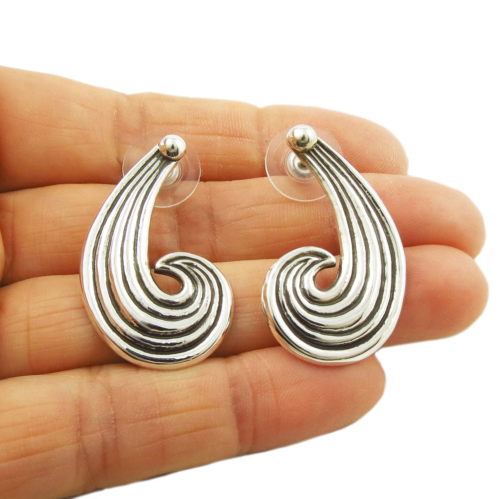 A pair of 925 sterling silver Taxco drop earrings held in a person's hand, featuring a swirl design.