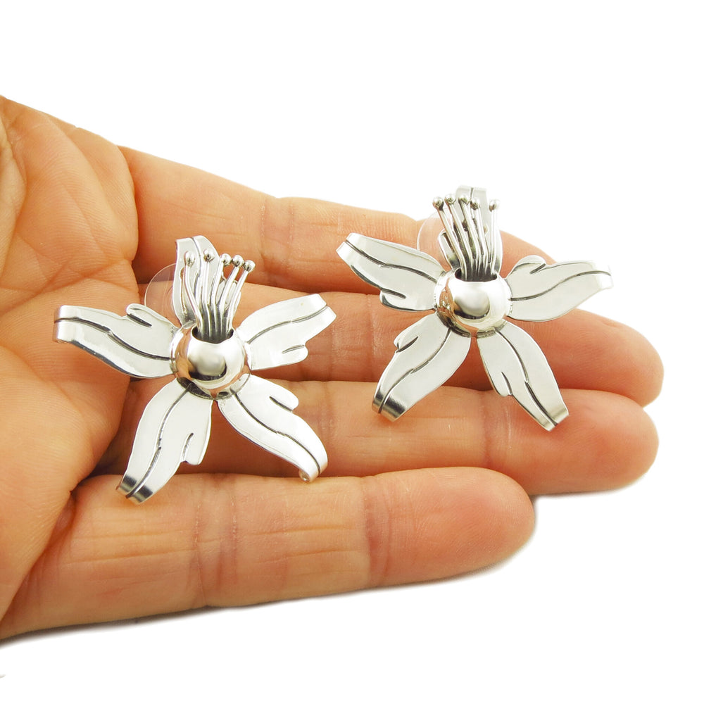 Sterling silver orchid earrings held in a person's hand.