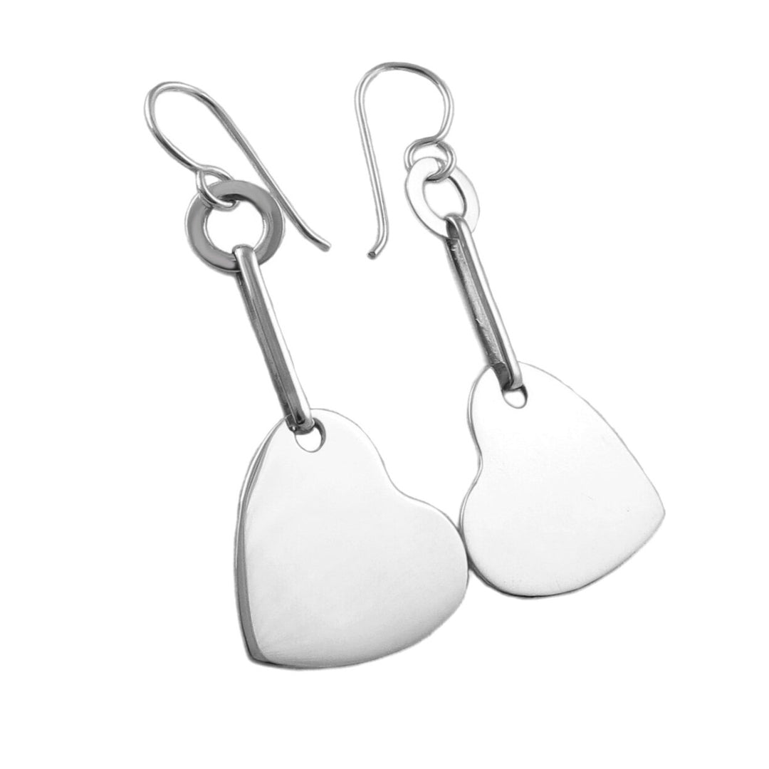 A pair of sterling silver dangle earrings with a heart design, suspended from silver hooks.