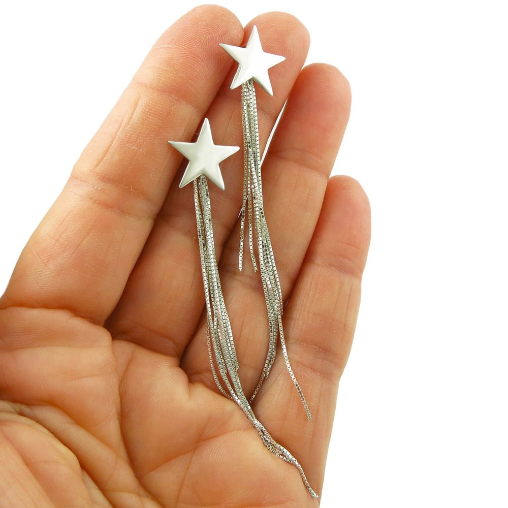 Sterling silver celestial star earrings with chain fringe held in a person's hand.