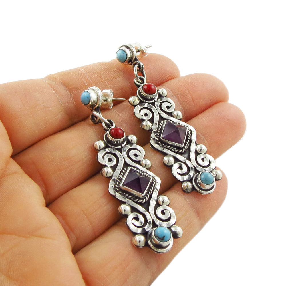 A pair of sterling silver baroque dangling earrings with turquoise and coral inlays, featuring amethyst gemstones.