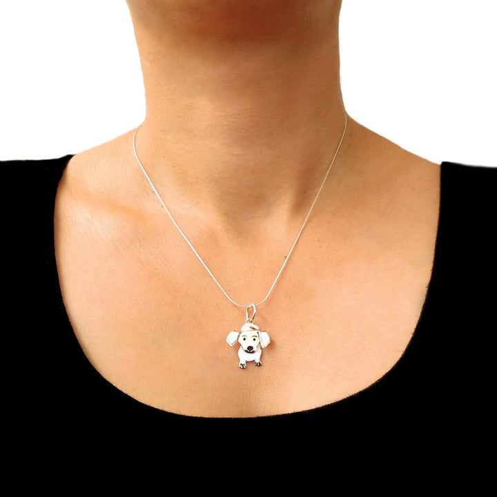A dachshund dog pendant and chain in 925 silver worn by a person with a black blouse.