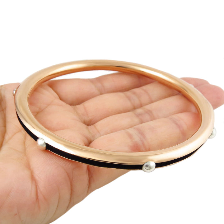 AA large polished copper circle bangle with 925 silver accents held in a person's hand on a white background. 