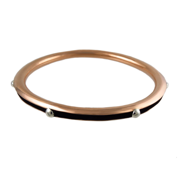 A large handmade circle bangle for women handwrought from polished copper with 925 silver accents on a white background. 
