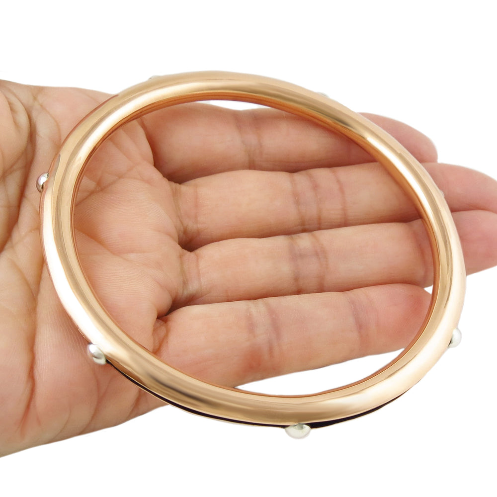 Large two tone copper and 925 silver bangle with small silver beads held in a hand on a white background