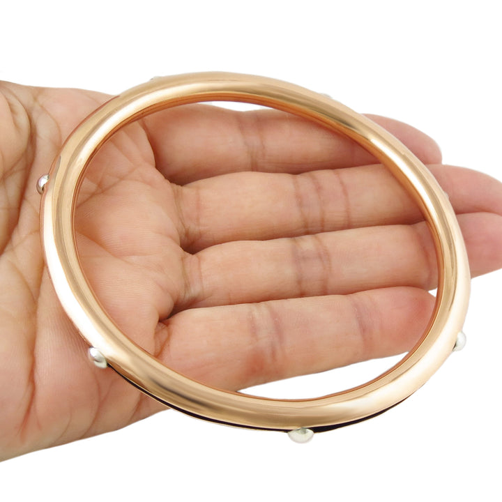 Large two tone copper and 925 silver bangle with small silver beads held in a hand on a white background