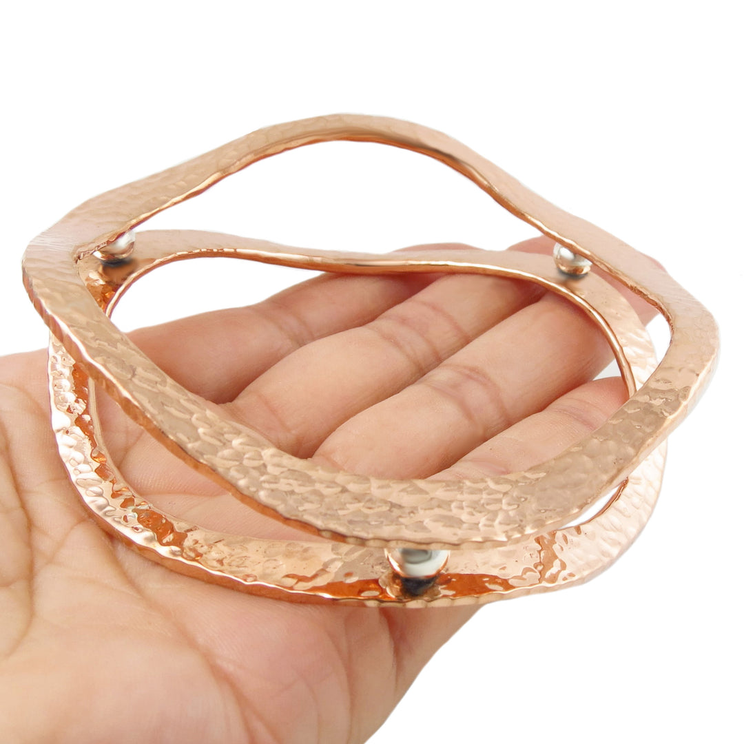 A large hammered copper and 925 silver double band designer bangle for women in a hand against a white background
