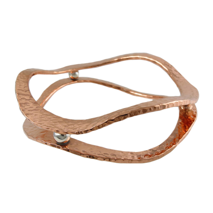 Mixed metal 925 silver and copper bangle with a hammered finish on a white background