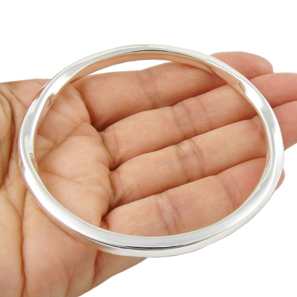 Silver bangle on a hand against a white background