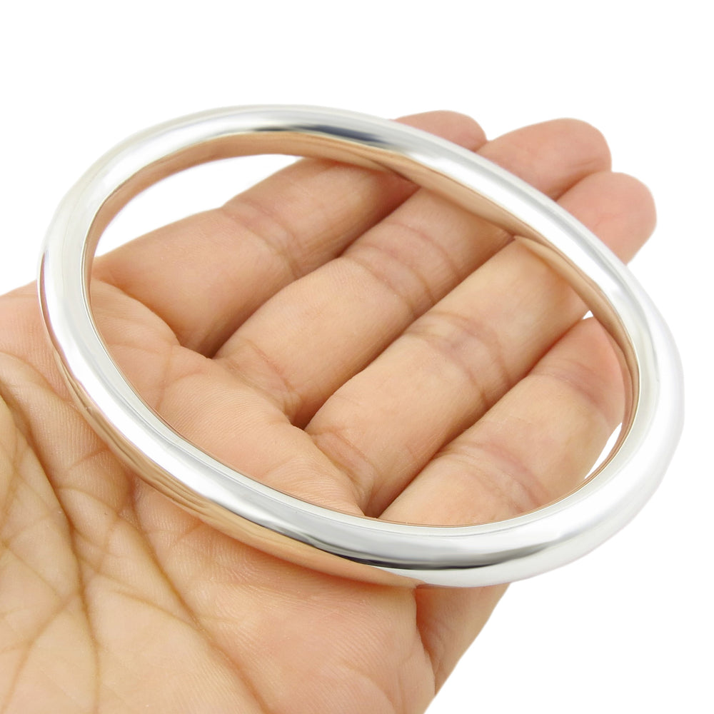 A large oval sterling silver tube bangle with a polished finish on a white background