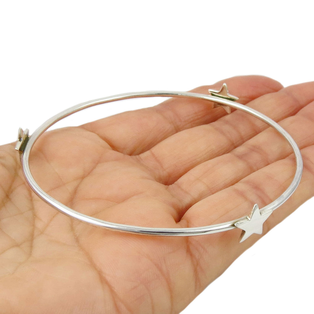 Sterling 925 silver ladies circle bangle with stars held in a hand on a white background