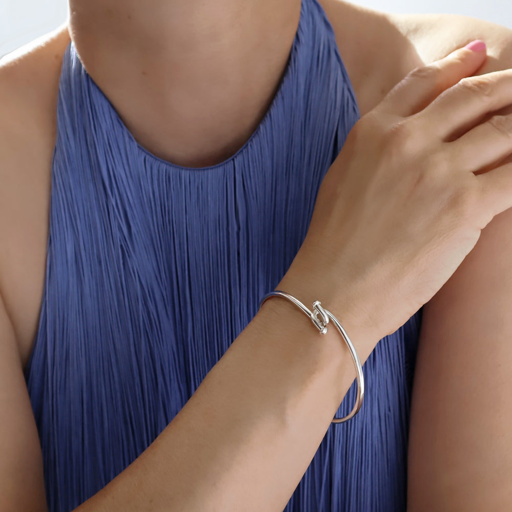 Person wearing a silver bracelet on a blue dress