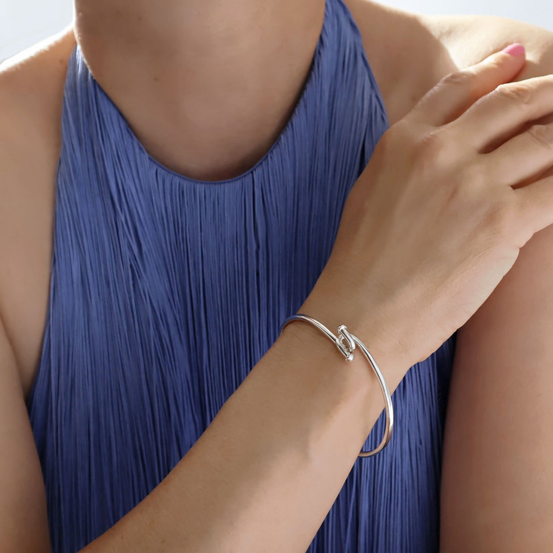 A front hook sterling 925 silver bangle worn by a woman in a blue dress