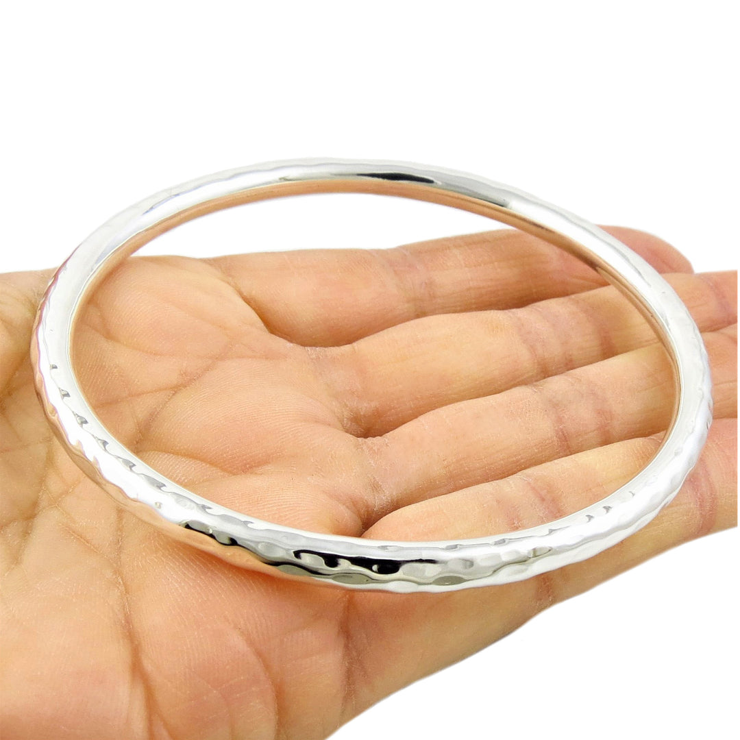Sterling 925 Silver hammered ladies bangle braceley on a hand against a white background