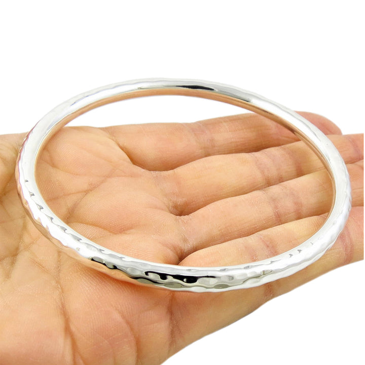 Sterling 925 Silver hammered ladies bangle braceley on a hand against a white background