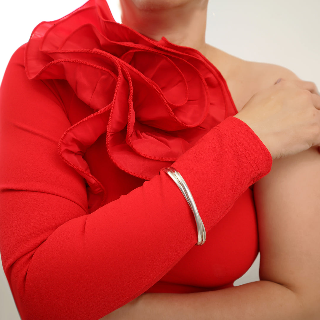 Woman in a red dress wearing a large oval infinity style interlocking sterling silver 2 in 1 bangle on one wrist