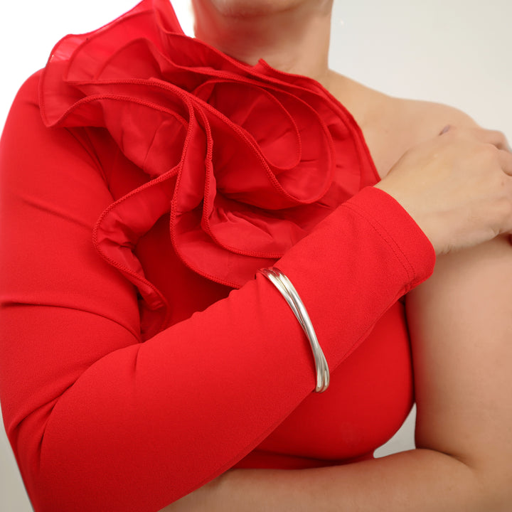 Woman in a red dress wearing a large oval infinity style interlocking sterling silver 2 in 1 bangle on one wrist