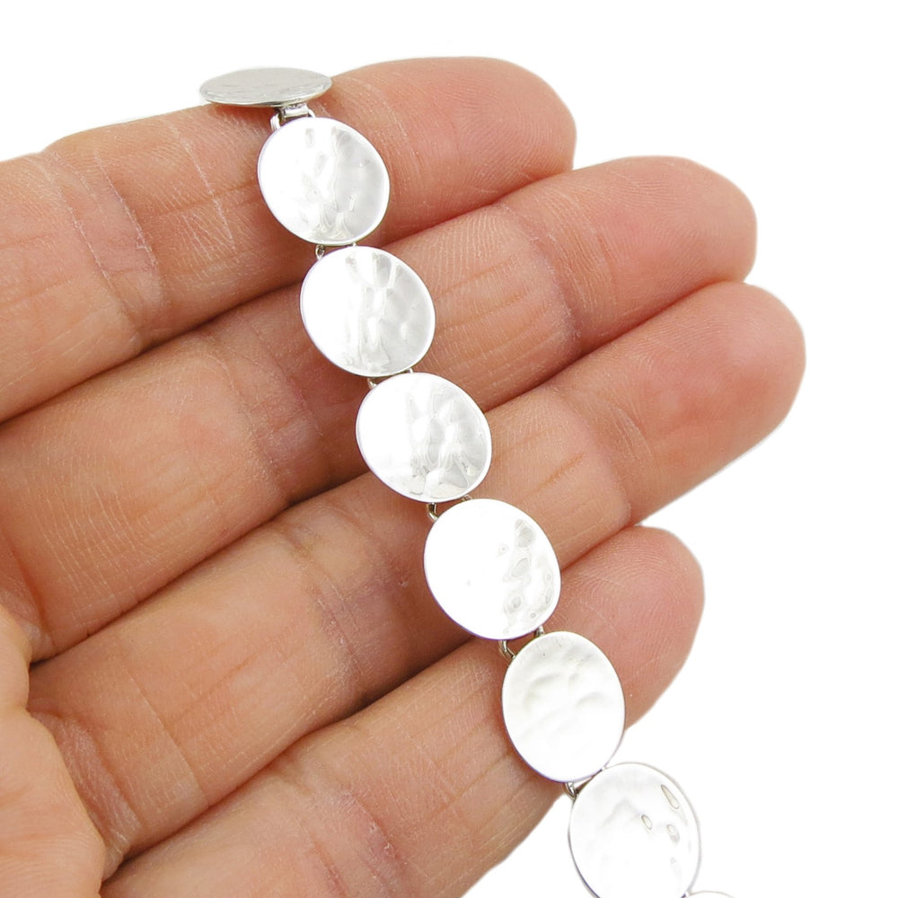 Hallmarked sterling 925 silver circle link bracelet with a hammered finish held in a female hand.