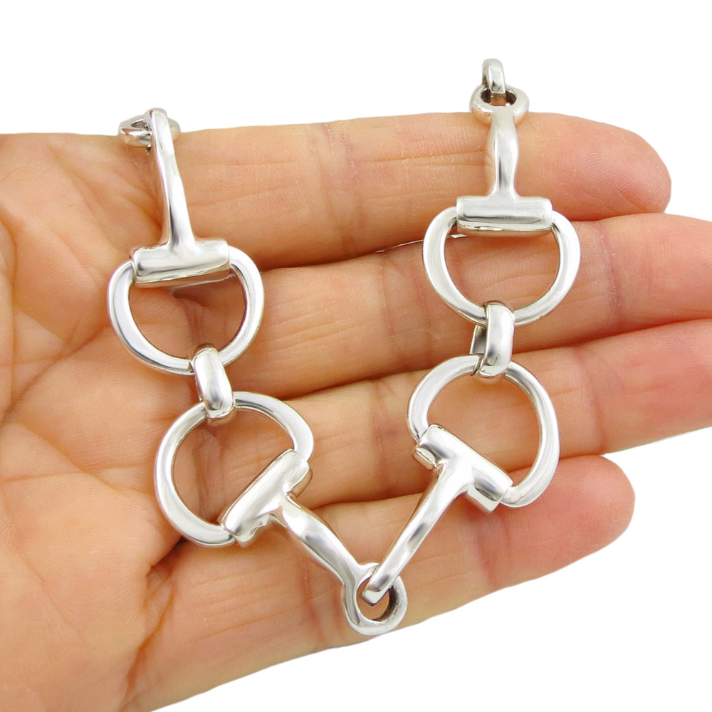 A hand holding a chunky 925 sterling silver horsebit snaffle ladies equestrian bracelet with a large t-bar toggle.