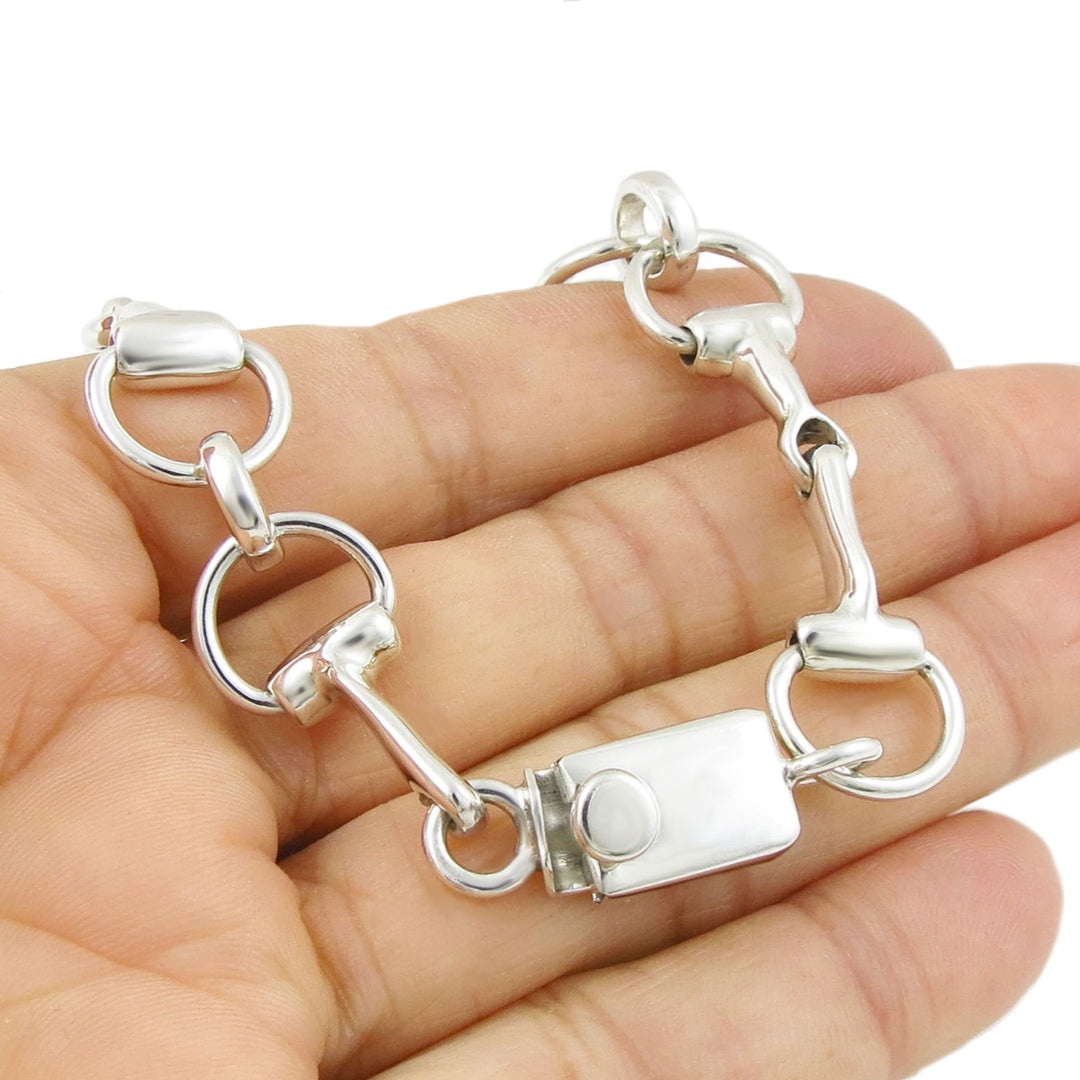 Sterling 925 Silver equestrian snaffle bracelet with a tongue and box clasp held in a hand on a white background.