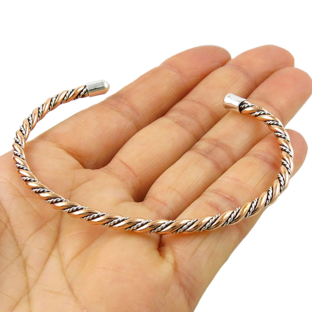 Sterling 925 silver and copper braided rope bracelet cuff on a hand against a white background