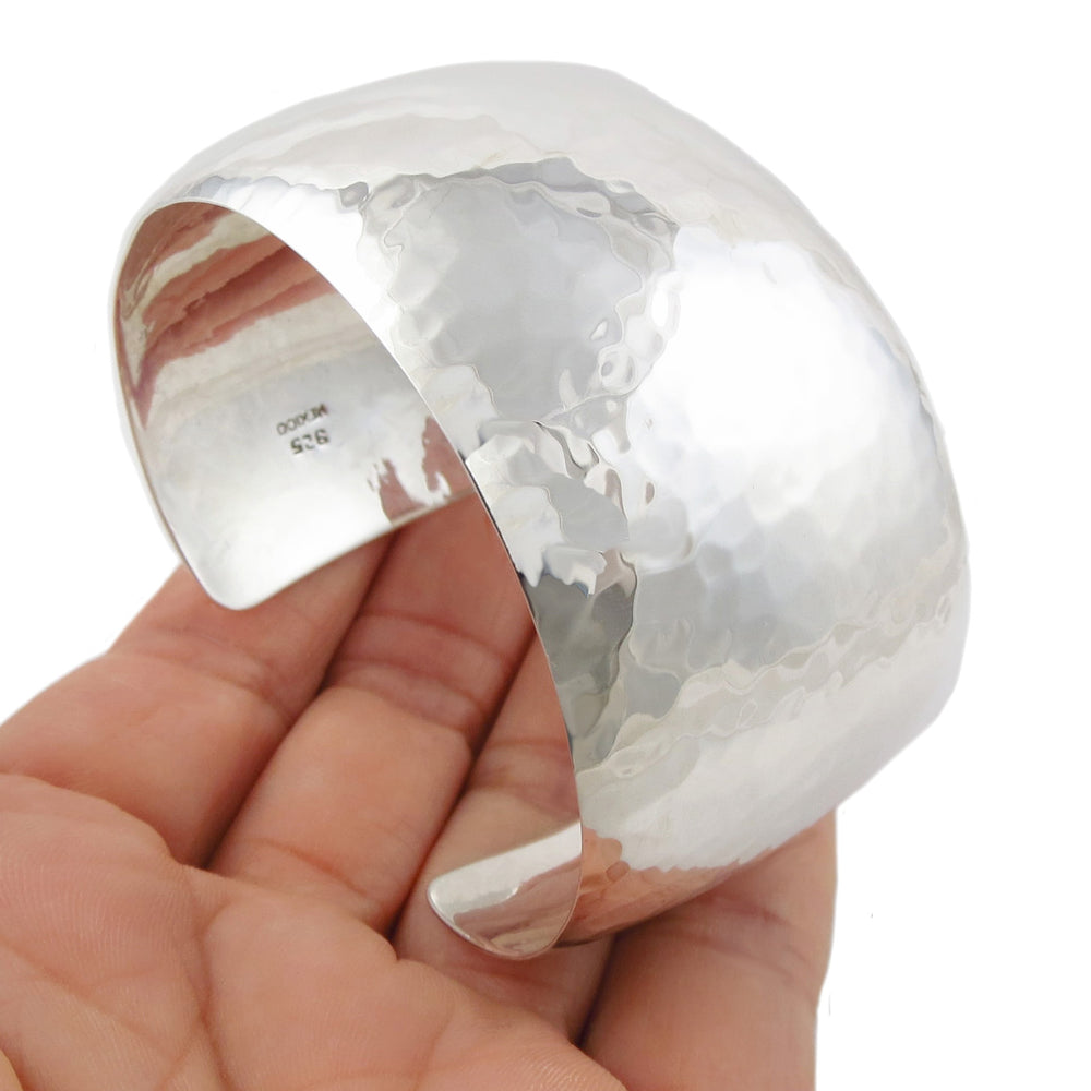 UK hallmarked large sterling 925 silver hammered bracelet cuff held in a woman's hand. 