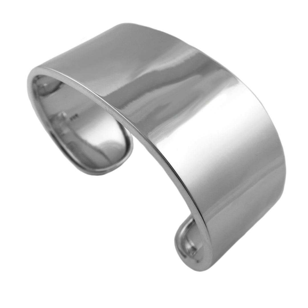 A wide silver cuff bracelet with a curved edge and a polished finish on a white background. 