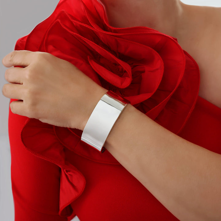 A woman in a red floral blouse blouse wearing a wide silver cuff with a polished finish. 