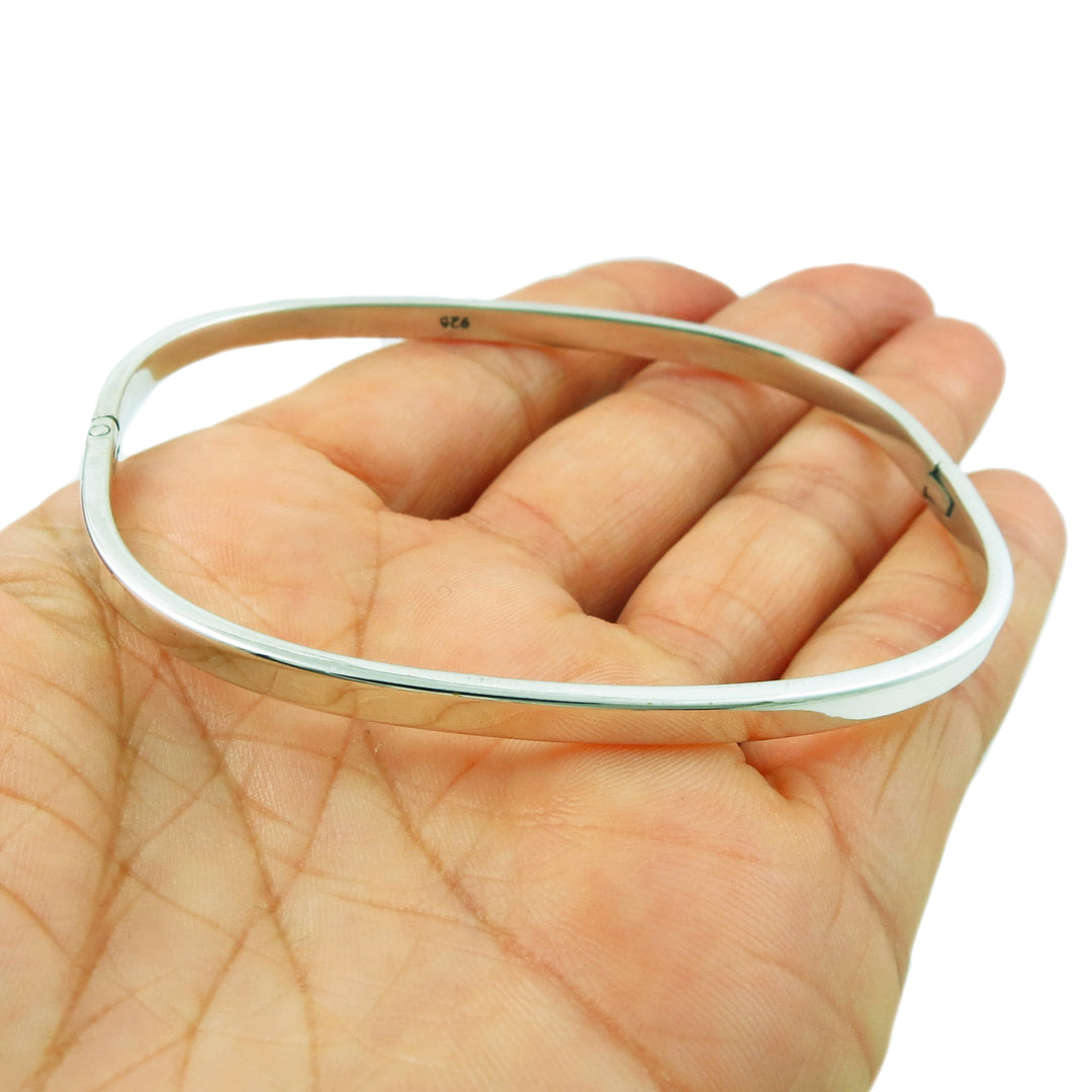 Silver bangle on a hand against a white background