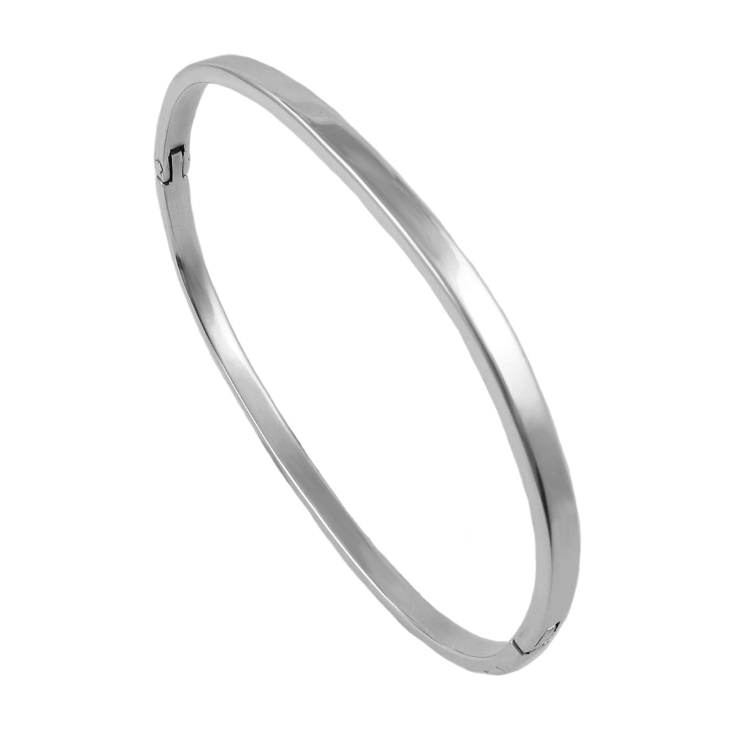 Oval solid silver bangle bracelet held in a person's hand on a white background. 