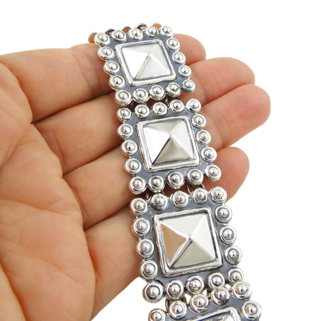 A large Mexican sterling 925 silver square link bracelet held in a person's hand on a plain background. 