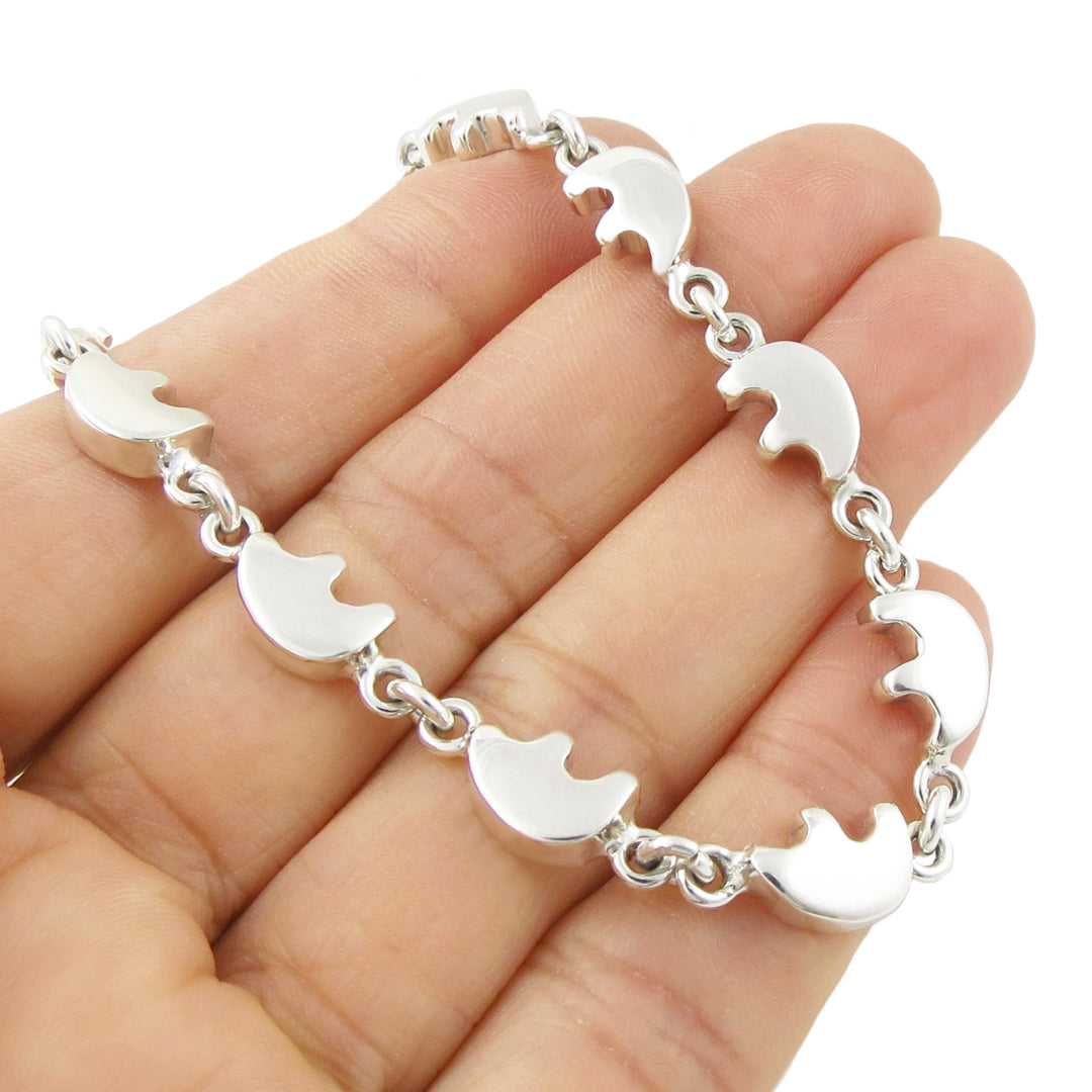 A UK hallmarked sterling silver bracelet with native american bear links held in a hand against a white background