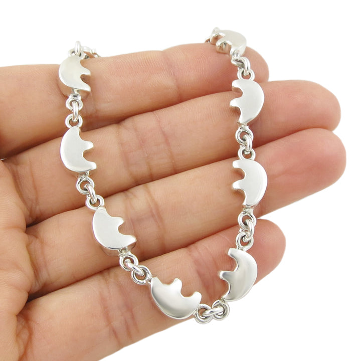 Solid 925 silver bracelet with native american bear links held on a hand against a white background