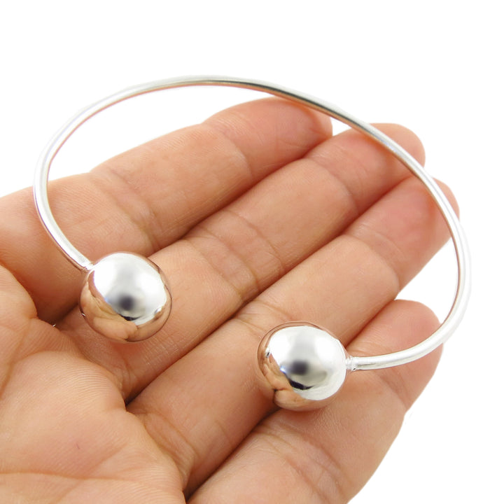  Mexican 925 sterling silver bracelet cuff with ball bead ends demonstrated in a female hand on a white background. 