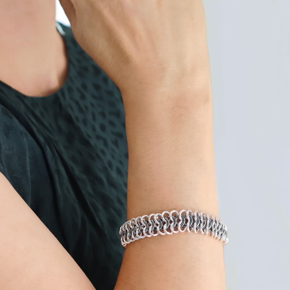 Silver bracelet on a person's wrist with a neutral background