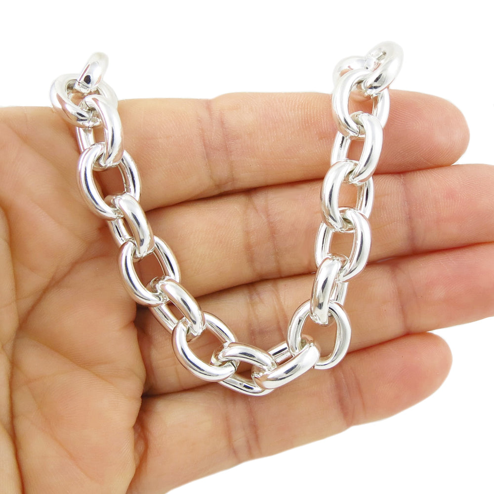Chunky silver chain bracelet held in a hand against a white background