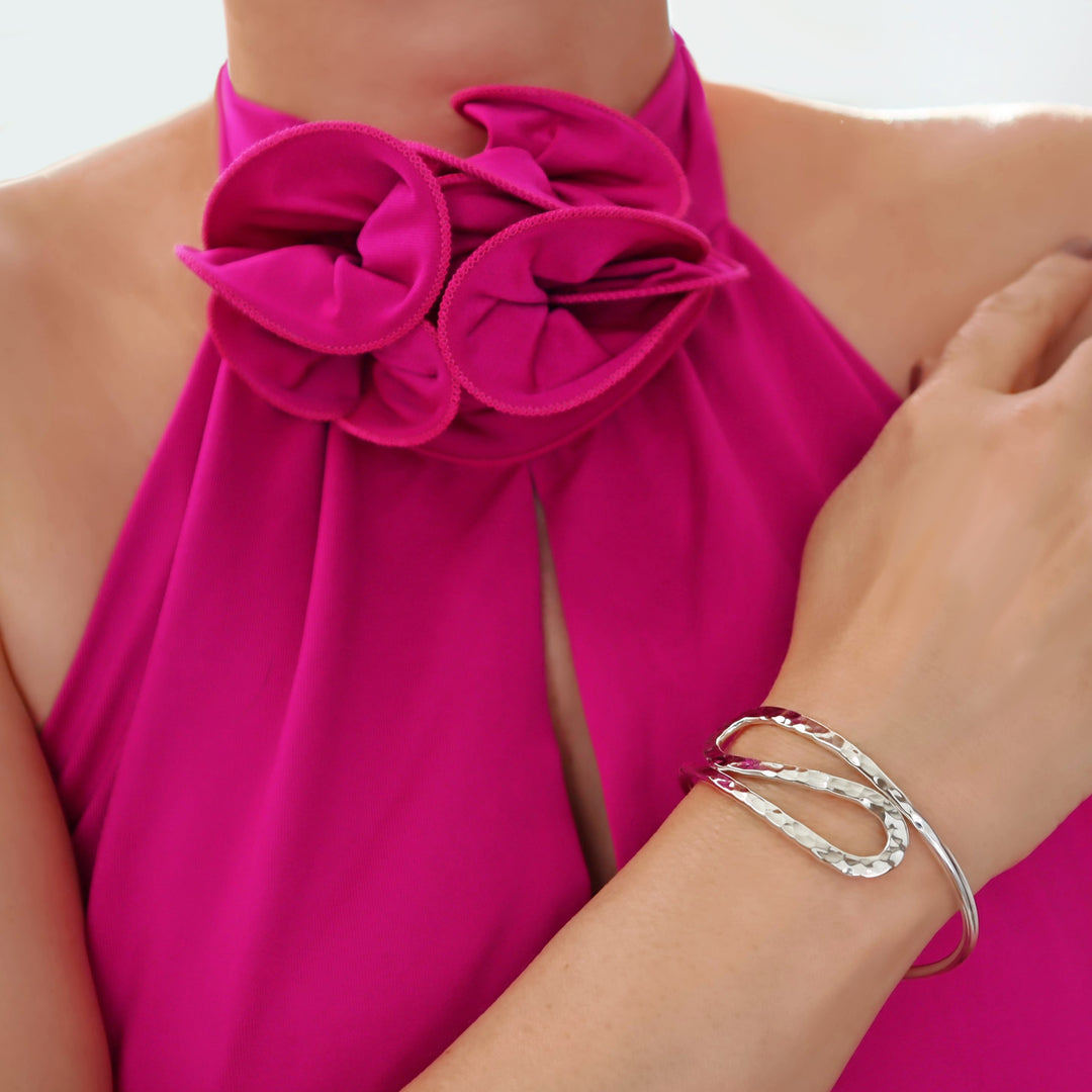 Woman wearing a pink top with floral details and a curved 925 silver bracelet on a white background