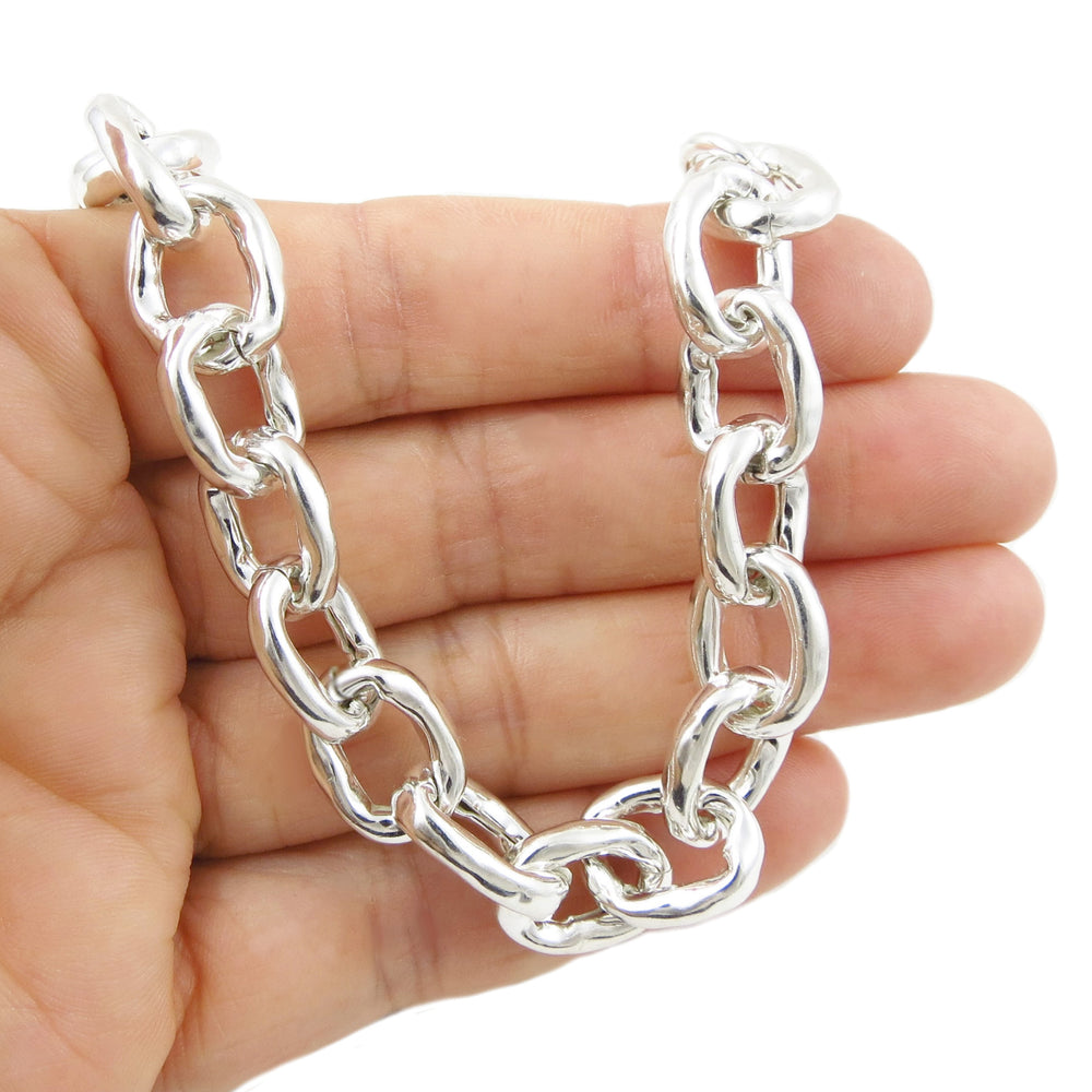Silver chunky chain bracelet held in a hand against a white background