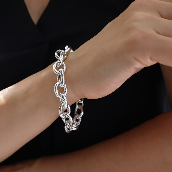Silver chunky chain bracelet on a wrist against a black background