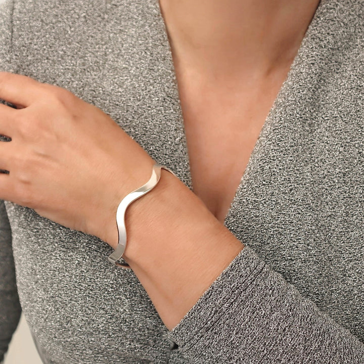 Sterling 925 Silver sculpted bracelet cuff on a woman's wrist with a textured gray sweater