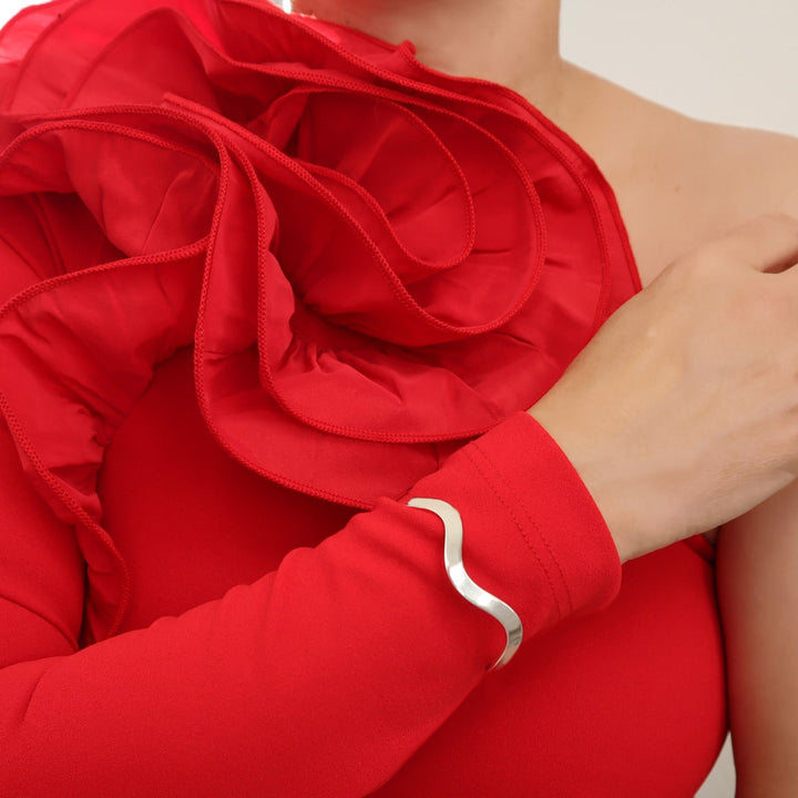 Wavy sterling 925 silver cuff bracelet worn by a woman in a fancy red dress with a frill