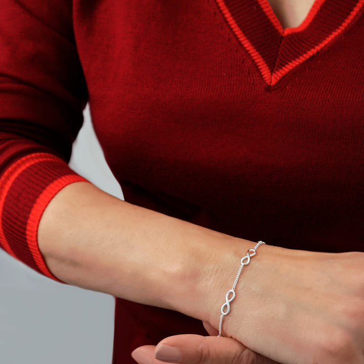 Woman wearing a 925 silver chain bracelet with an infinity symbol on a red sweater.