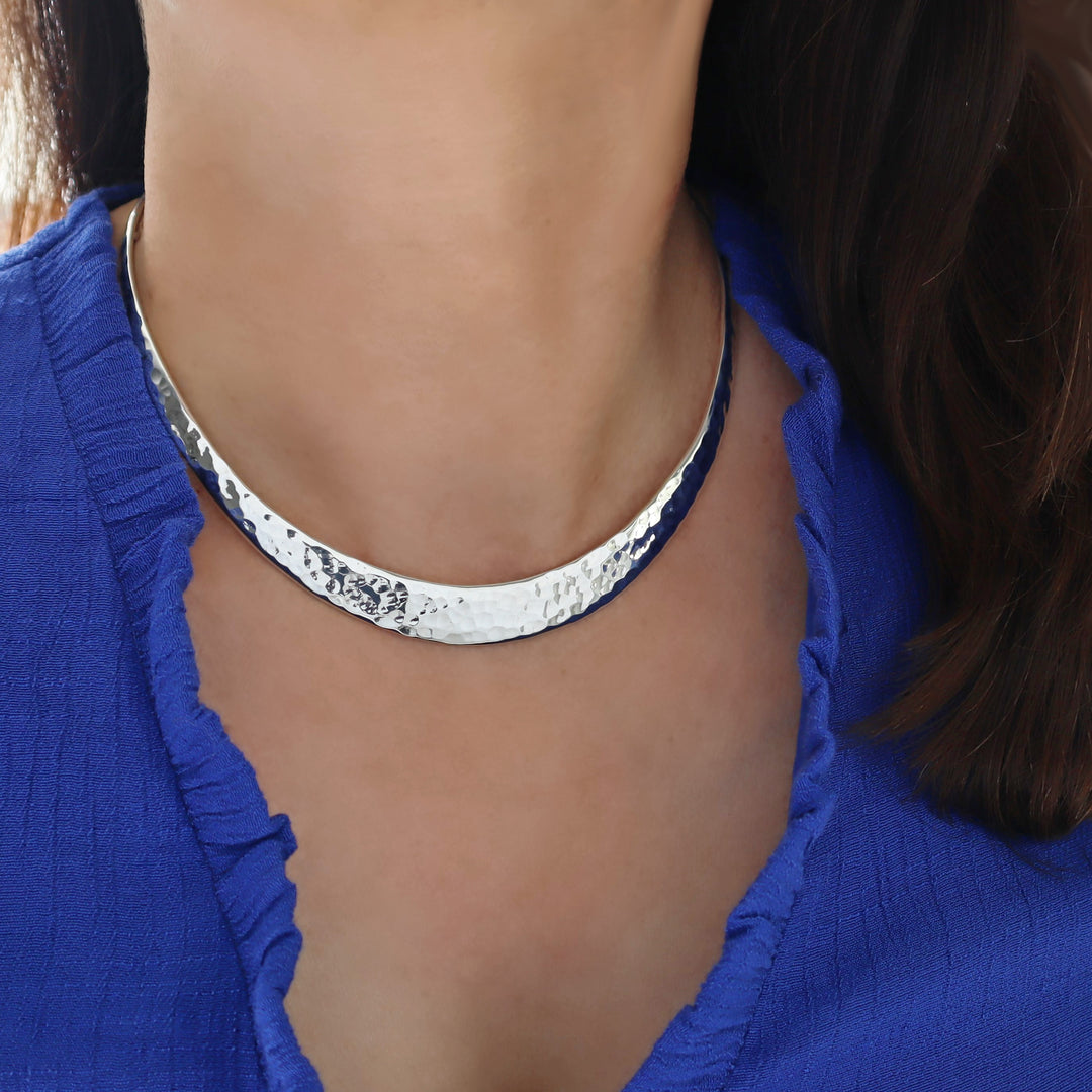 Hammered silver choker necklace worn by a person in a blue top