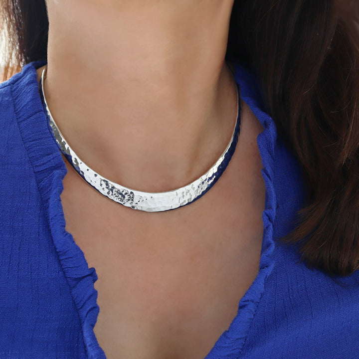 Hammered silver choker necklace worn by a person in a blue top