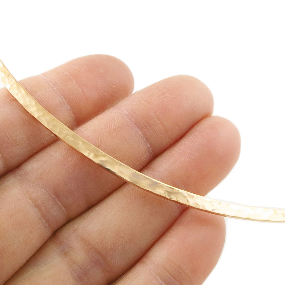 Hammered copper ladies choker torc on a hand against a white background