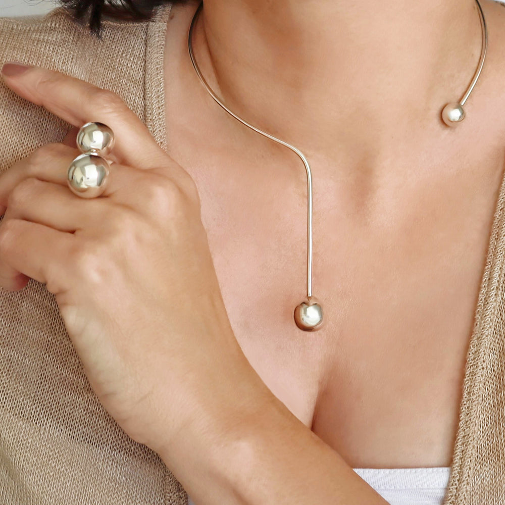 A woman wearing a sterling silver choker necklace with ball beads, with a close-up on her neck.