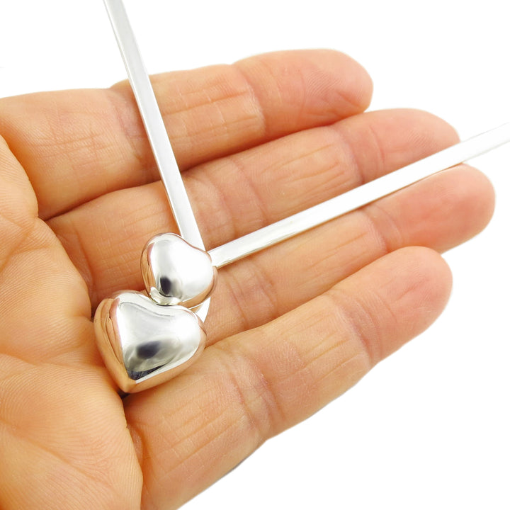 A close-up of a woman's hand holding a sterling 925 silver choker necklace with heart charm accents at the front of the design. 