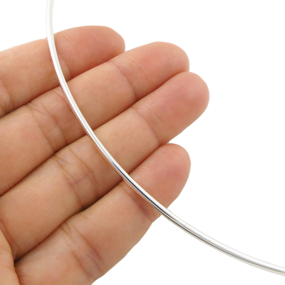 A thin, polished sterling 925 silver choker toque held in a woman's hand against a plain white background.