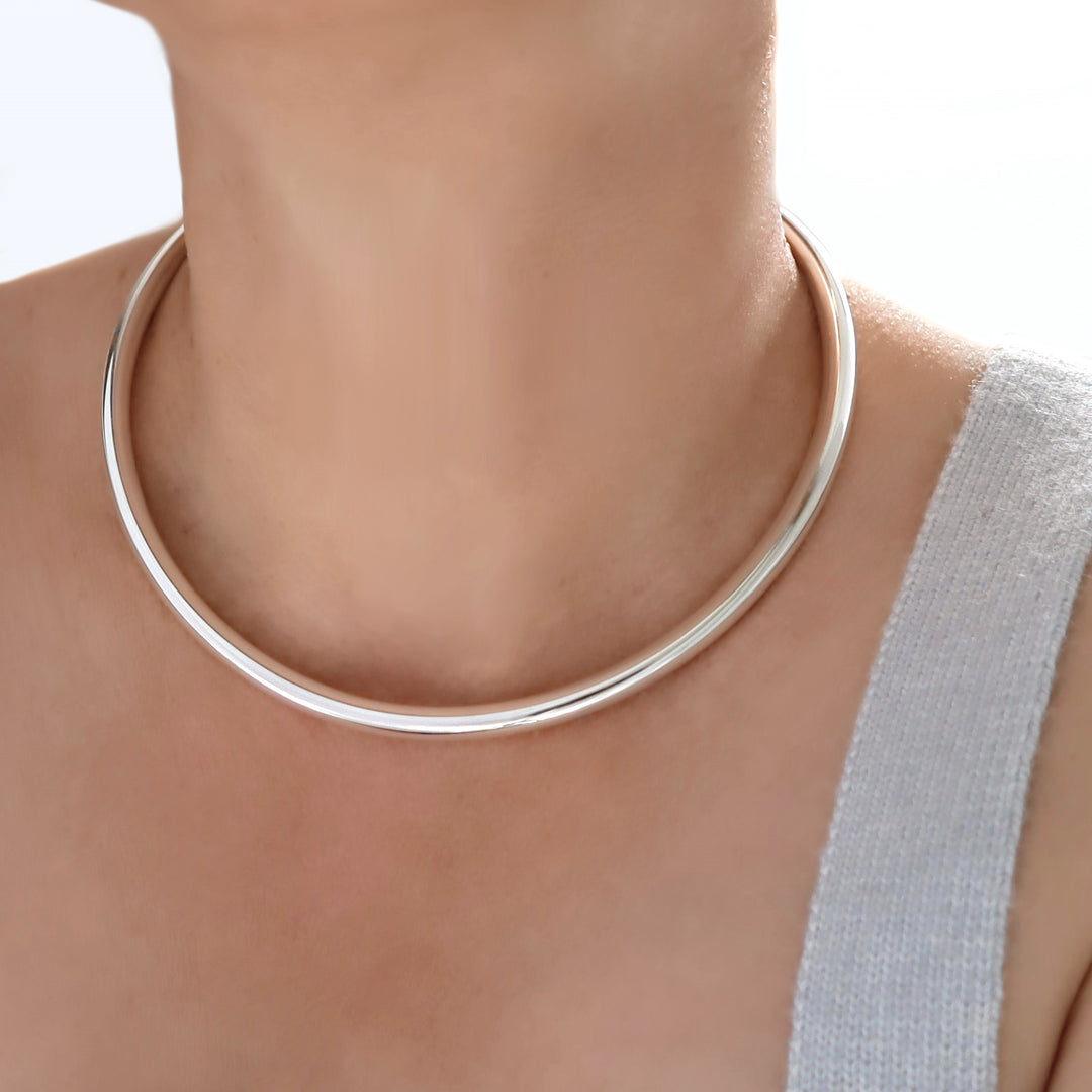 Silver tube choker necklace on a person with a neutral background