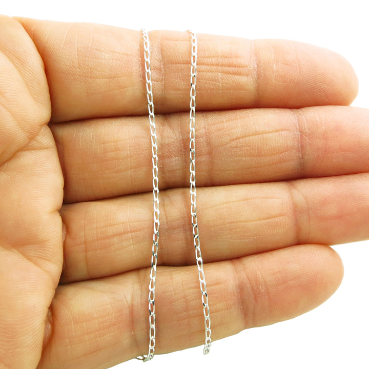 A sterling 925 silver curb chain necklace held in a woman's hand on a white background. 
